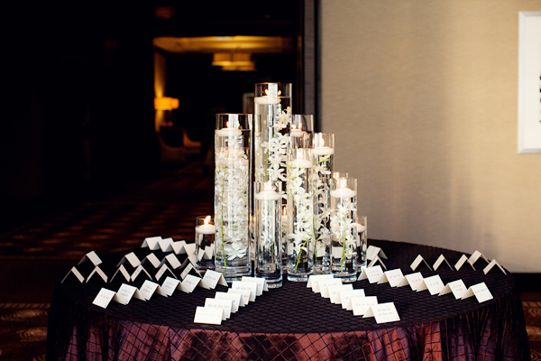 Vases with orchids and candles floating in water and white escort cards - Photo by Olivia Leigh Photographie